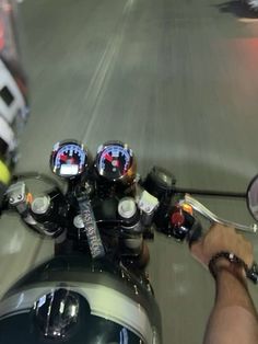 a person riding a motorcycle down a street next to a traffic light and helmet on the handlebars