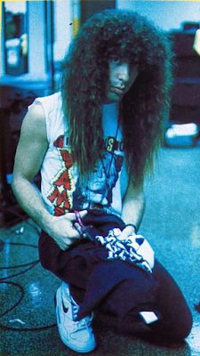 a man with long hair sitting on the ground