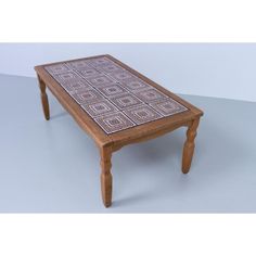 a small wooden table with an intricate design on the top and legs, sitting on a plain surface