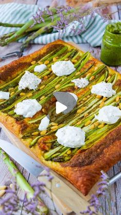 asparagus and goat cheese quiche on a wooden cutting board next to flowers