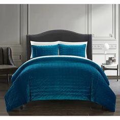 a bed with a blue comforter and pillows