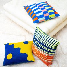 three colorful pillows sitting on top of a white blanket