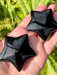 two black glass stars are held in someone's hand