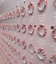 several pairs of pink and white beaded hoop earrings are hanging on a display wall