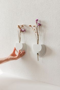 two white plates with flowers on them are attached to the wall, and one is holding another plate