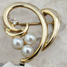 This is the perfect option for those who like cool, unique jewelry, and luxury. This brooch is well made, cute and/or elegant in design, and very desirable. The brooch is decorated with 3 pearls and a diamond. It has the shape of a heart. The clasp is in very good working condition. ♥ Age/Era: Circa before the 2002s. ♥ There is a hallmark. 14K. ♥ The brooch is about 1'' by 1''. ♥ The weight is about 4.3 gr. Everyone interested in the jewelry should remember that he or she must like their jewelry Elegant Heart-shaped Wedding Brooch, Yellow Gold Fine Jewelry Brooches For Anniversary, Fine Jewelry Yellow Gold Anniversary Brooches, Elegant Gold Brooch For Valentine's Day, Elegant Gold Brooches For Valentine's Day, Elegant Brooch For Valentine's Day, Elegant Valentine's Day Brooch Jewelry, Elegant Valentine's Day Brooch, Elegant Wedding Pins For Valentine's Day