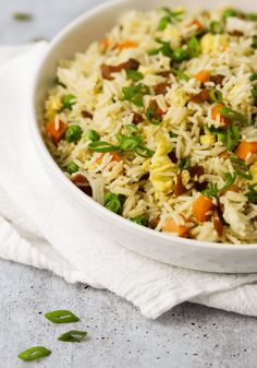 a bowl filled with rice and vegetables on top of a white cloth next to a fork