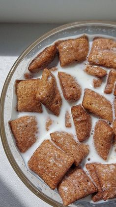 a glass bowl filled with sugar cubes and milk on top of a white table