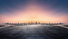 an empty parking lot with the city skyline in the background at sunset or sunrise time