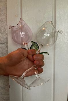 a hand holding two clear vases with flowers in them on a door handle that is attached to a white wall