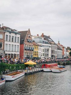 several boats are docked on the water in front of some buildings and people sitting at tables