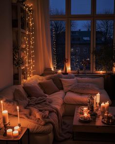 a living room filled with lots of candles next to a couch and table in front of a window