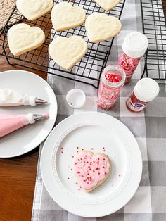 a table topped with white plates and heart shaped cookies