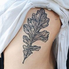 a black and white photo of a leaf on the back of a woman's stomach