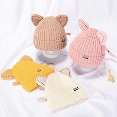 three knitted hats with ears on top of each one and two smaller ones in the middle