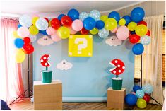 a room decorated with balloons and mario birthday decorations