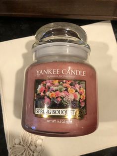 yankee candle spring bouquet in glass jar sitting on top of a white napkin next to a lace doily