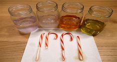 candy canes are lined up next to jars with liquid in them on a paper towel