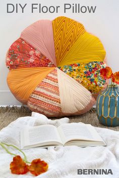 an open book is sitting on the floor next to some colorful pillows and vases