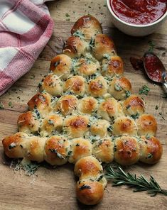 a christmas tree made out of bread on a cutting board next to some dipping sauce