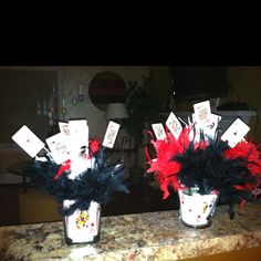 two vases filled with cards and feathers on top of a counter