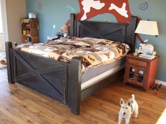 a dog standing next to a bed in a room with blue walls and wooden floors