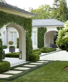 a white house with green plants on the front yard