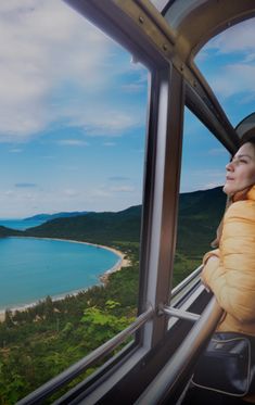 a woman is looking out the window of a cable car on top of a mountain