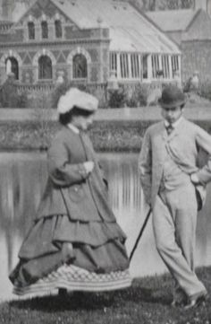 an old black and white photo of two people standing next to each other in front of a lake