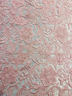 an image of a pink lace fabric with flowers and swirls on the back side