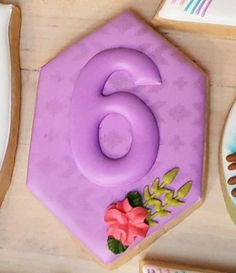 a number six shaped cake sitting on top of a table next to other decorated cookies