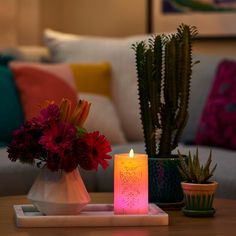 a lit candle sitting on top of a table next to a vase filled with flowers