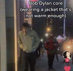 a man standing in the middle of a street with his hands on his hips and texting that reads, bob dyan core wearing a jacket that's not warm enough