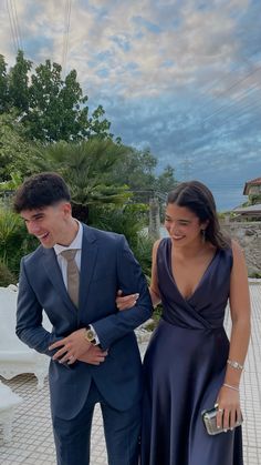 a man and woman in formal wear standing next to each other on a brick walkway