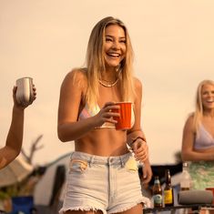 two women standing next to each other holding cups