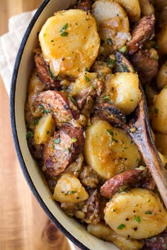 a bowl filled with potatoes and meat on top of a wooden table