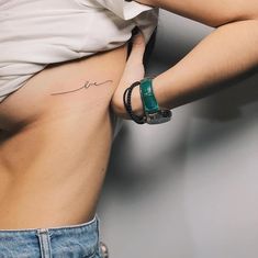 a woman's stomach with a small tattoo on her left side and the word love written in cursive writing