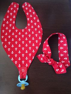 a red bib with white anchors on it and a blue pacifier in the foreground