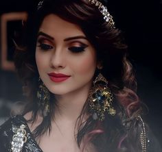 a woman with dark makeup and gold jewelry on her head, posing for the camera