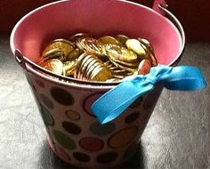 a bucket full of gold coins with a blue bow on the top and another one in the background