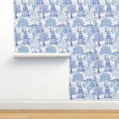 a blue and white wallpaper with trees and houses on it, next to a wooden floor