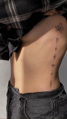 the back of a woman's stomach with flowers on it and a cross tattoo