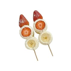 three strawberries and one banana on a stick with some fruit cut in half to look like they are sitting together