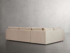 a large beige couch sitting on top of a floor next to a white wall and gray walls