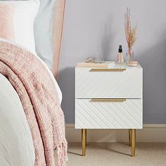 a white nightstand next to a bed in a room with gray walls and pink accents