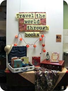 there is a suitcase and some books on the table in front of this sign that says travel the world through books