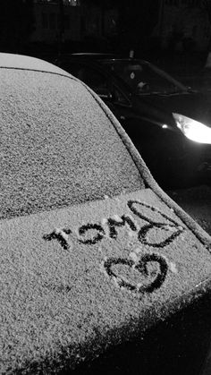 a car is parked on the side of the road covered in snow and has graffiti written on it