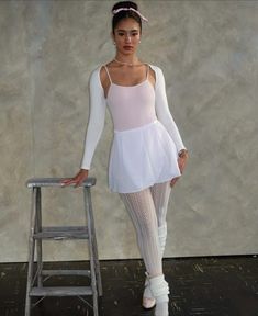 a woman standing next to a stool wearing tights