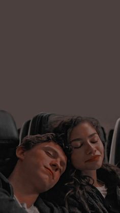 a man and woman laying down on an airplane with their eyes closed while they are asleep