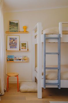 there is a bunk bed in the room with pictures on the wall and a small stool next to it